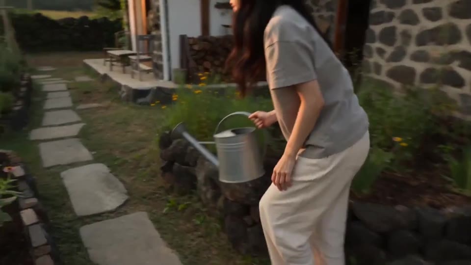 Adult hand watering a dry planter in an original cottage garden